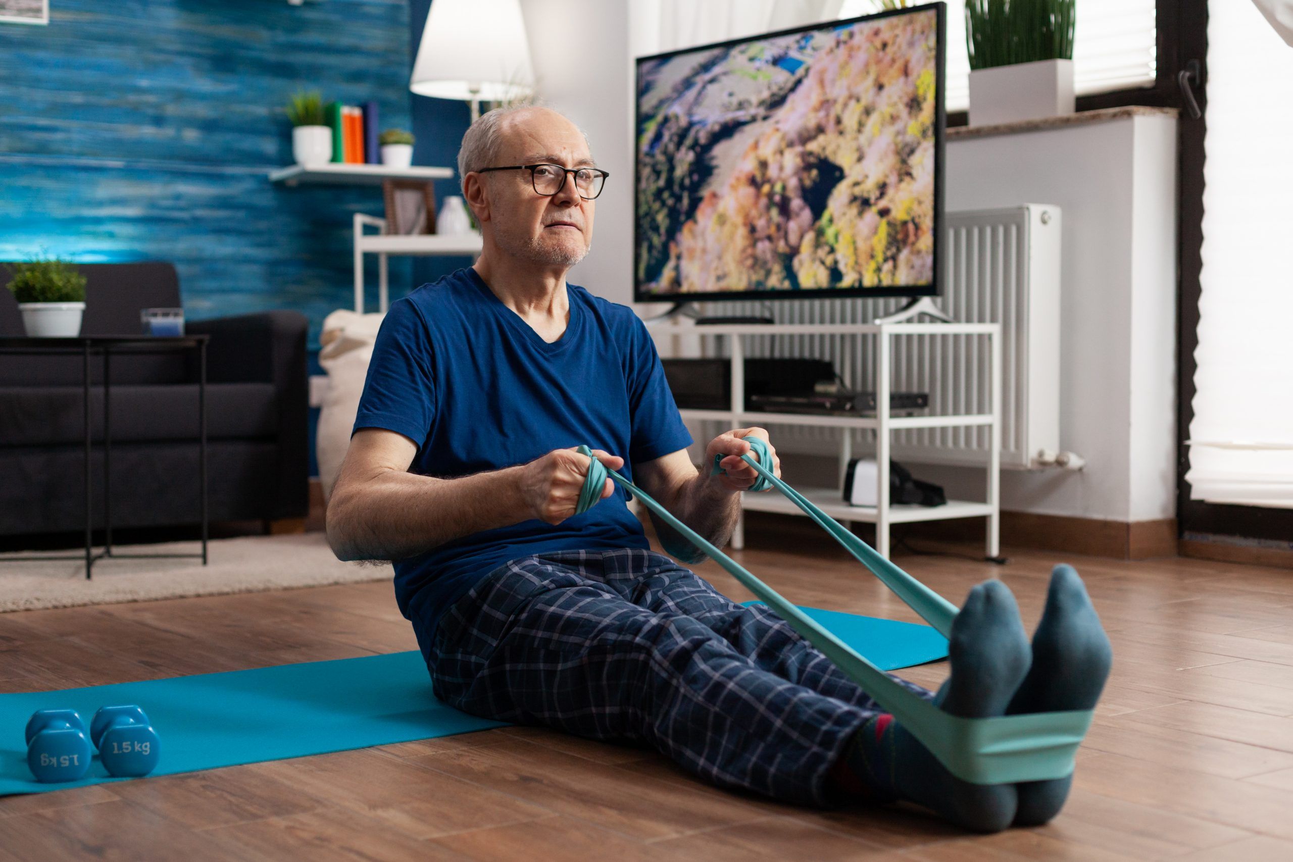 Retirement senior man sitting on yoga mat stretching legs muscles